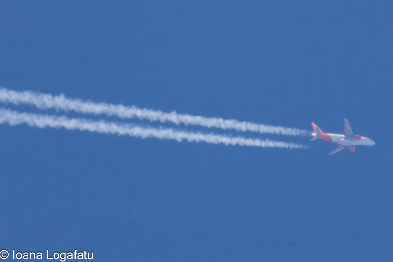 Jet soaring through a clear blue sky with trails